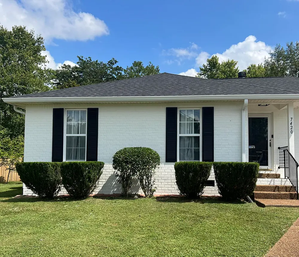 minimalist exterior painting project of a white house with black window shutters