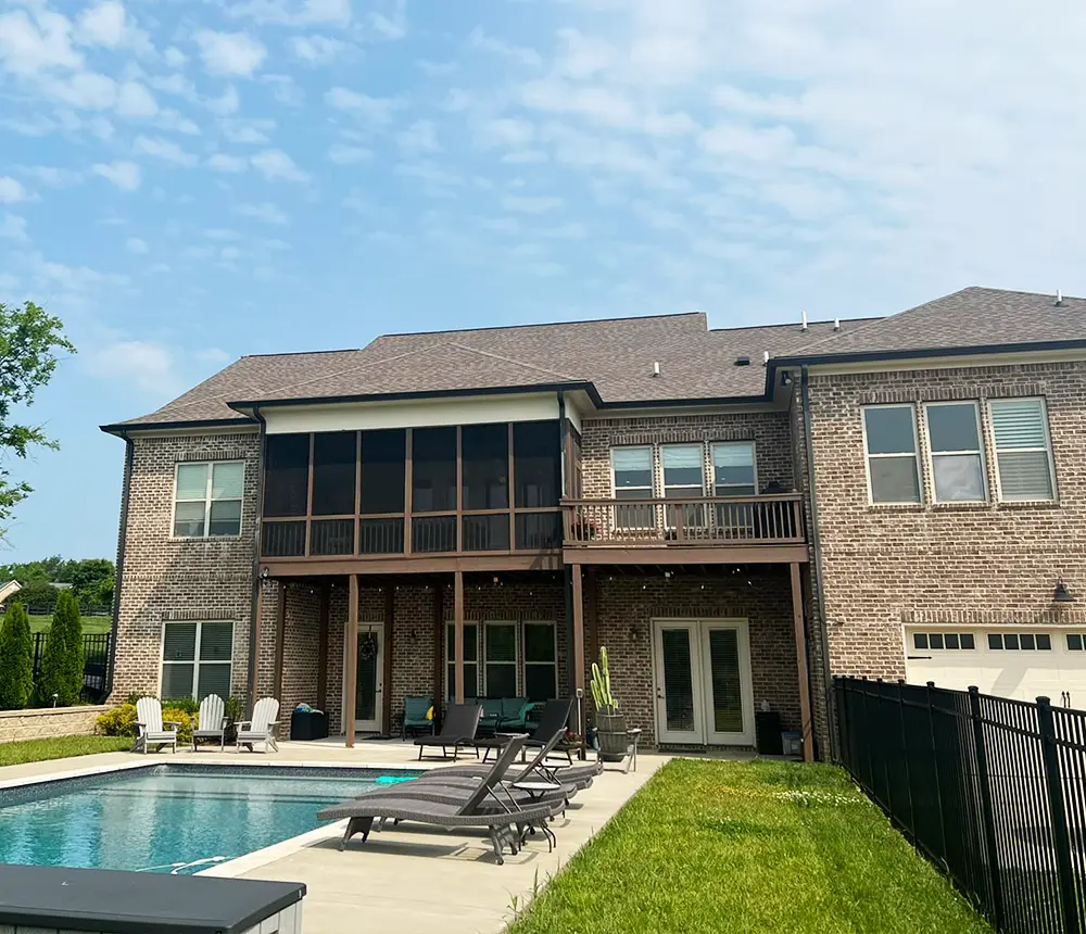 brick house with pool and lawn