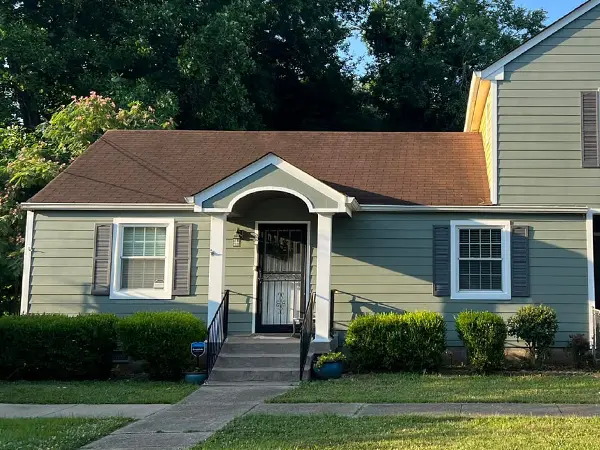 a house with a porch and a door, painted grey