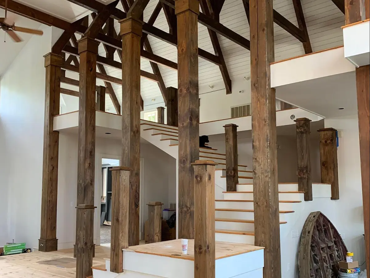 a staircase inside a house with big wooden support pillars, painted brown