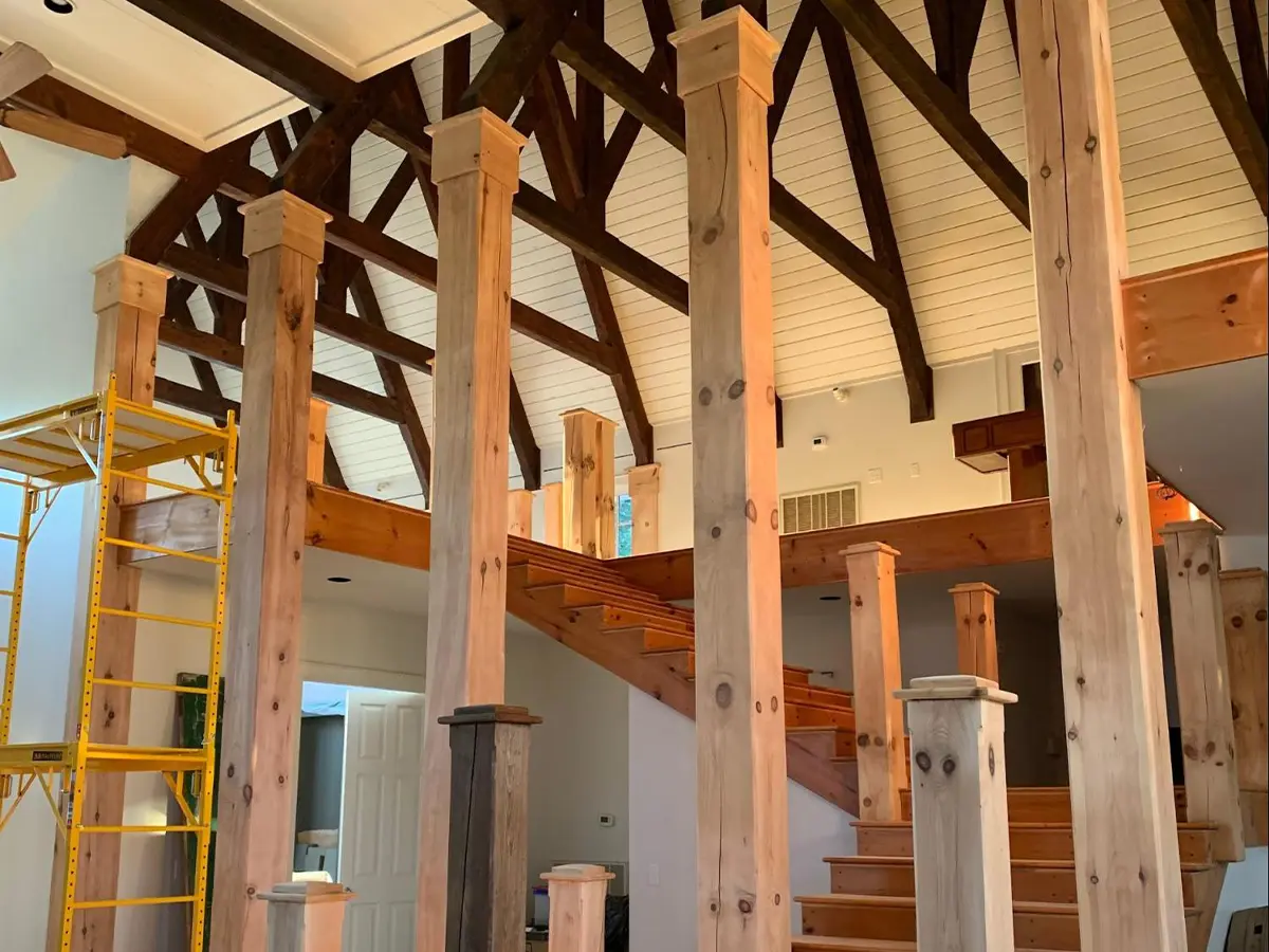 a staircase inside a house with big wooden support pillars, not painted