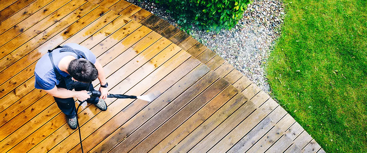 Worker spraying through wooden deck before painting process