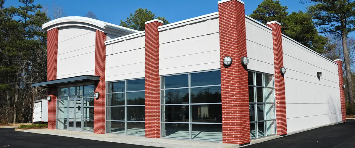 Modern commercial building exterior with red brick columns and large glass windows, ideal for office or retail space design.